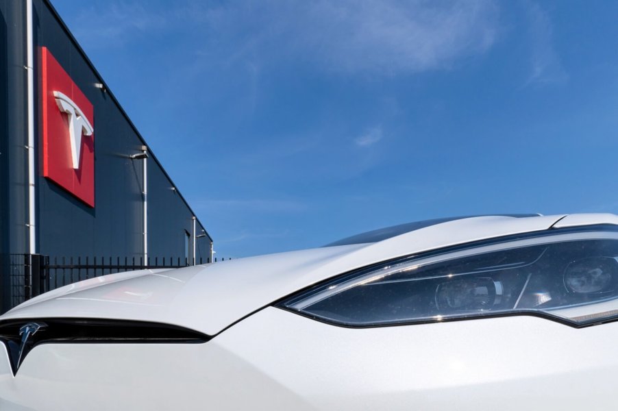 A Tesla Model S near a storefront with its badge prominently displayed.