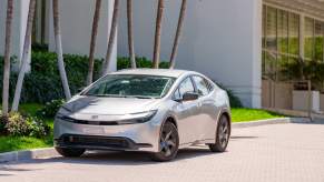 New 2023/2024 Toyota Prius parked in front of palm trees, stylish large wheels limiting its MPG