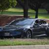 Black used Tesla car parked in a neighborhood, its value depreciation faster than Maserati