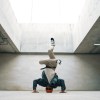 A breakdancer doing a headstand wearing sunglasses in a modern cement structure