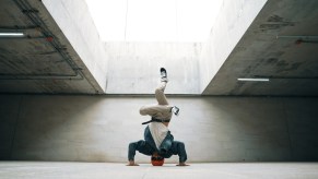 A breakdancer doing a headstand wearing sunglasses in a modern cement structure