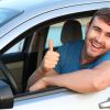 A driver in a car wearing blue short gives thumbs up signal