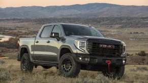 GMC pickup parked on grassy elevated lane in front of a valley and mountain in right front angle view