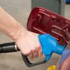 A hand pumping gas into a car at a gas station in very close view