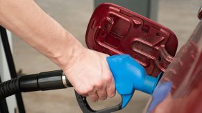 A hand pumping gas into a car at a gas station in very close view