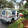 A mail carrier delivering letters in a USPS mail truck