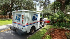 A mail carrier delivering letters in a USPS mail truck