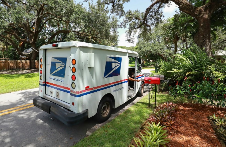 A mail carrier delivering letters in a USPS mail truck