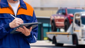 A man with a clipboard near a tow truck