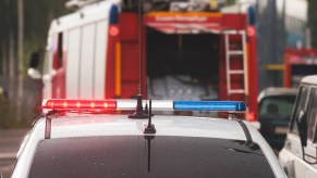 A police car with lights on by a firetruck