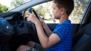 A little boy driving an SUV