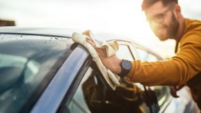 Man using a towel to wipe car exterior roof area