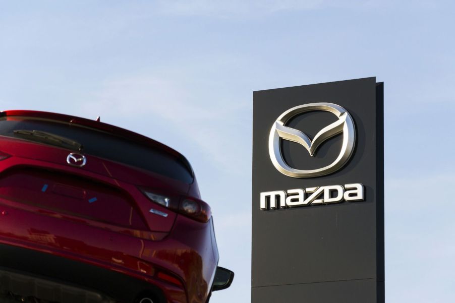 A Mazda3's rear end, with a Mazda dealership sign in the background