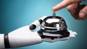 Robot hand holds a service bell while human hand presses bell top