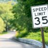 35 mph speed limit sign on a green brush-lined rural road