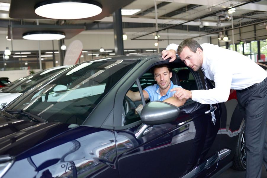 A car salesman offering a test drive to a potential dealership customer