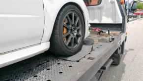 A white car on the flatbed of a tow truck