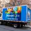 A Walmart home delivery truck parked on a residential street in left rear angle view