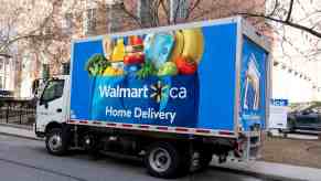 A Walmart home delivery truck parked on a residential street in left rear angle view