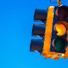 Yellow traffic light signal in close view hanging up against blue sky